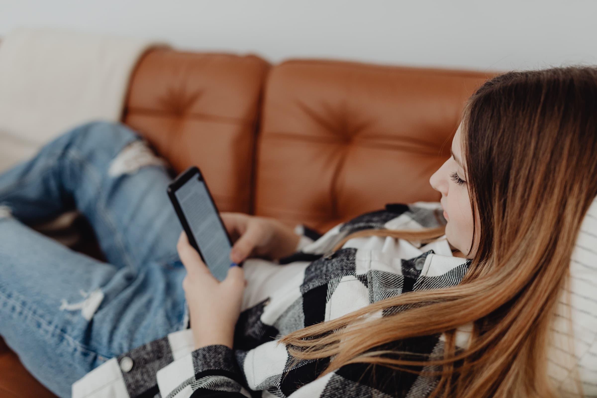 A shopper relaxing on a leather sofa, reading her phone